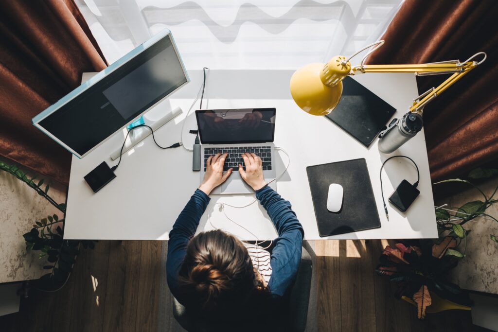 A woman types on her laptop at her desk